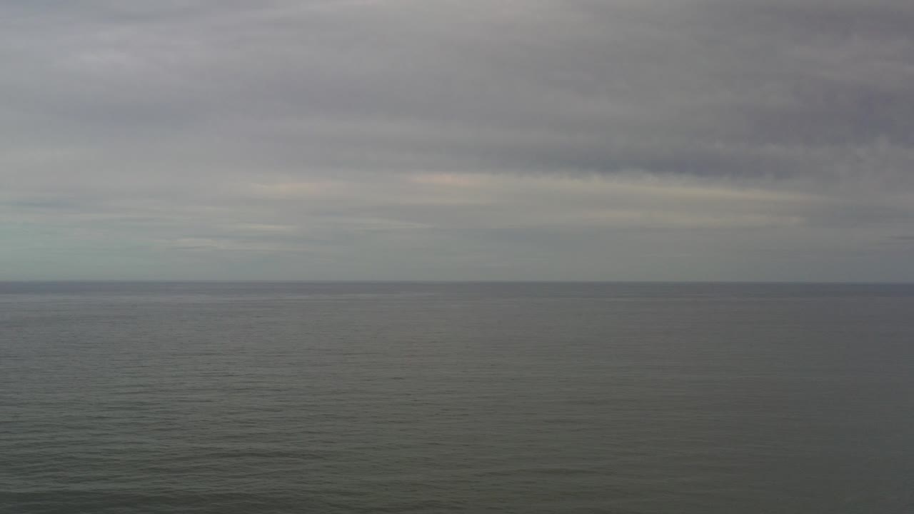 Wide ocean horizon beneath gray clouds