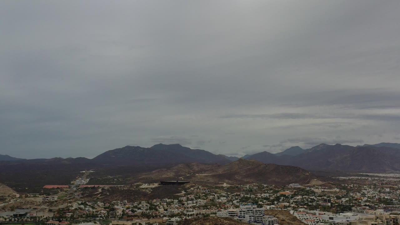 Wide cityscape with hills and gray cloud cover.