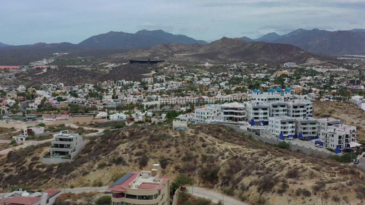 Residential hillside with apartment blocks and mountain range beyond.