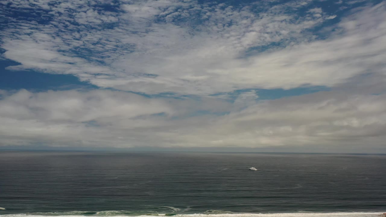 At 0:01, the Los Cabos ocean fills the frame beneath broken clouds, with a small white boat offshore and no visible people.