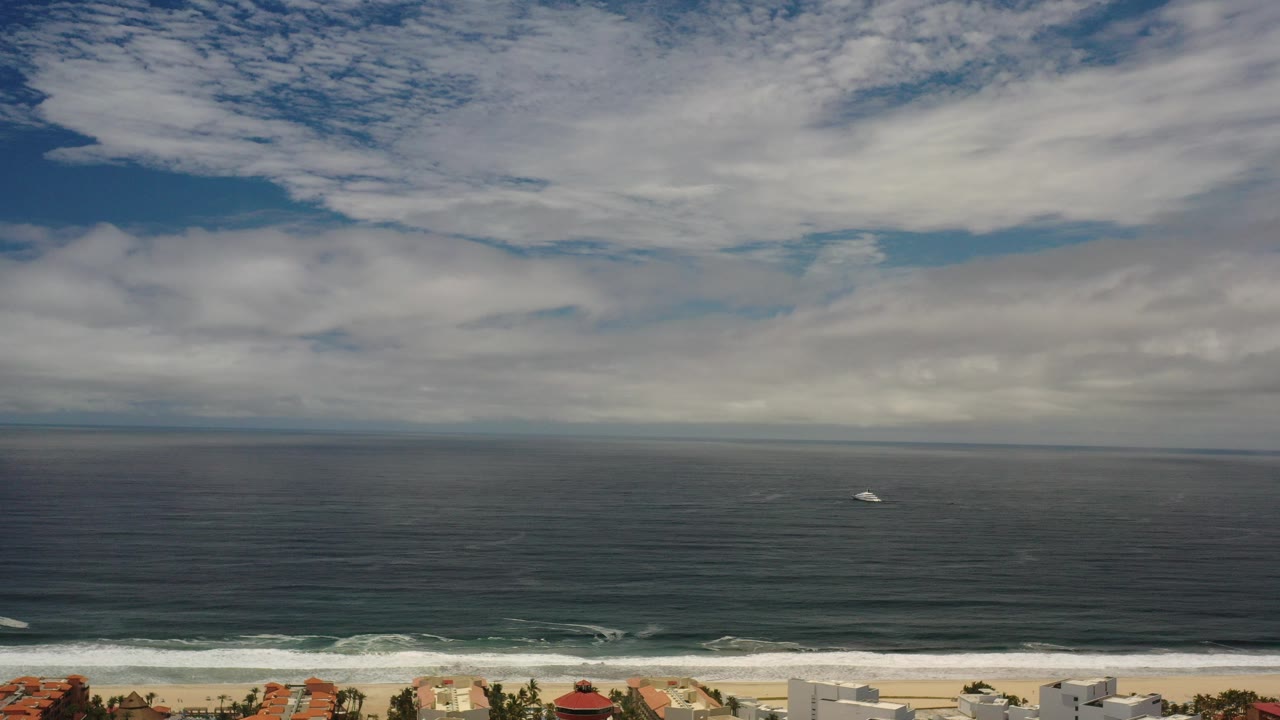 Wide ocean horizon under layered clouds above a beach