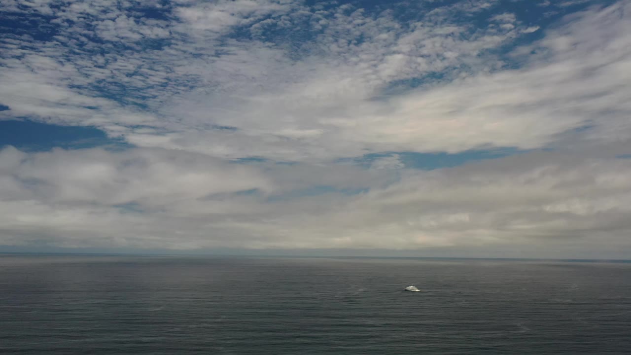The Los Cabos coastline view remains offshore, with heavy cloud bands filling the upper frame, dark water below, and no visible people.