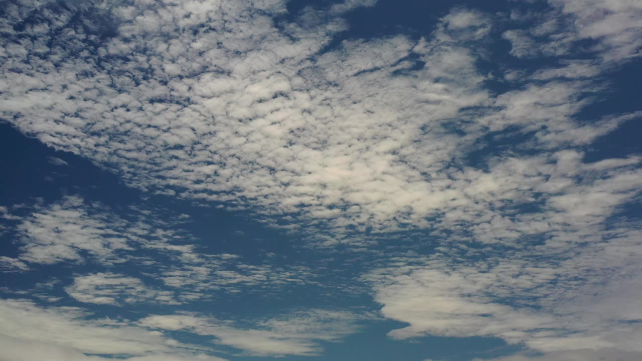 Patchy white cloud bands cover the upper blue sky in Los Cabos, Mexico, with darker open sky showing between them and no visible people.