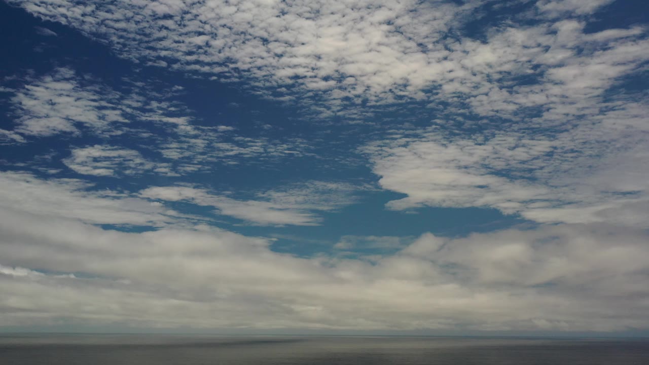 Cloud bank over a dark ocean line in daylight.