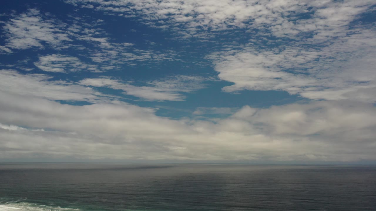Wide ocean horizon beneath broken clouds.