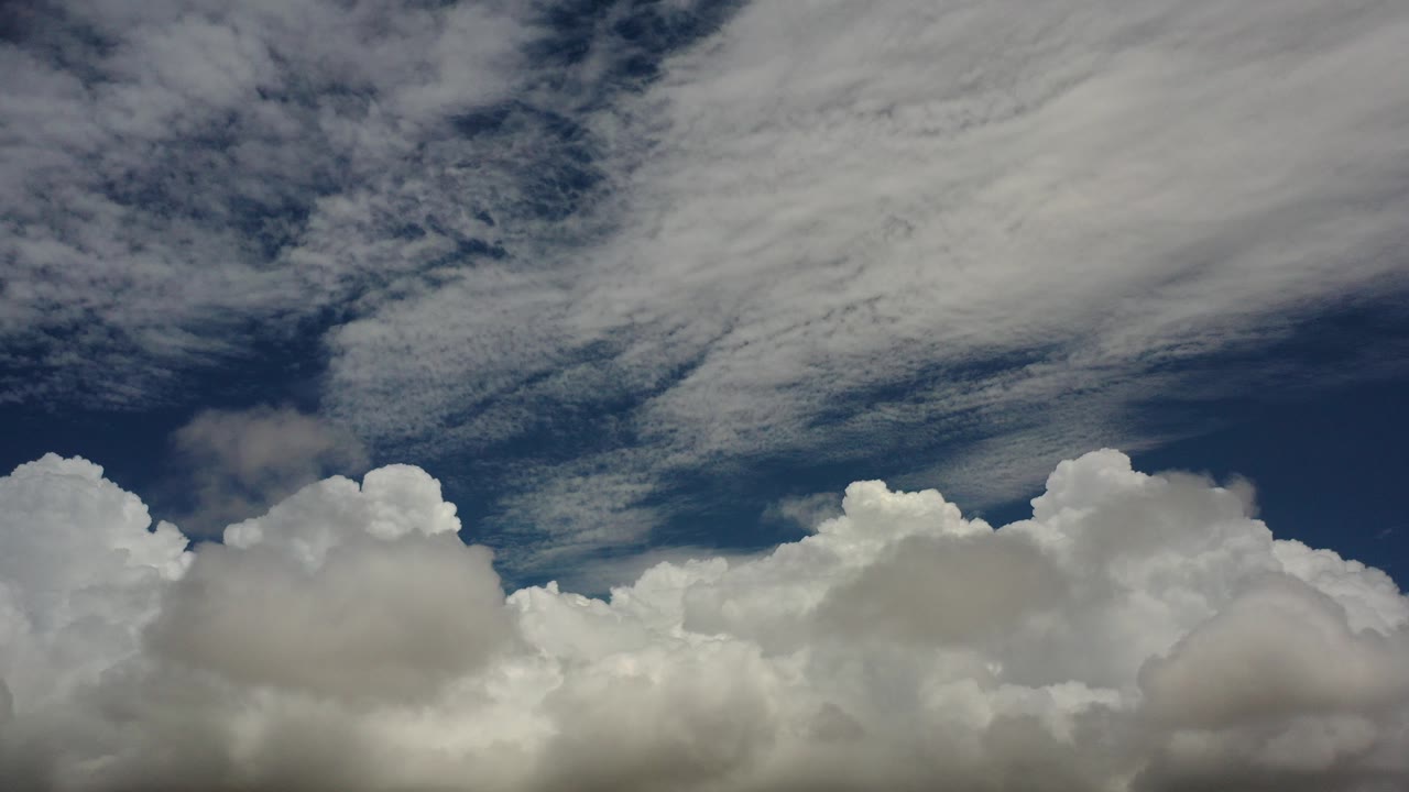 At the start of the Los Cabos clip, white cloud banks sit low against a deep blue sky with streaked cloud texture above and no visible people.