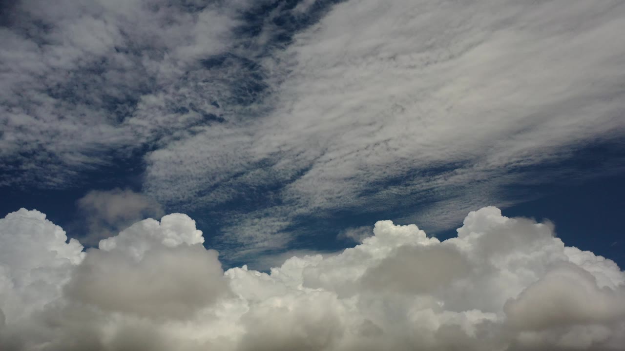 Dense white clouds below a darker blue opening in the sky.
