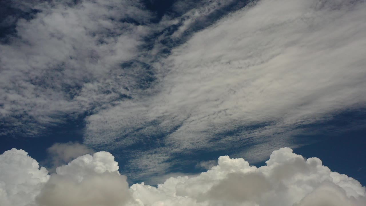 Blue sky with layered white clouds and cumulus along the bottom edge.