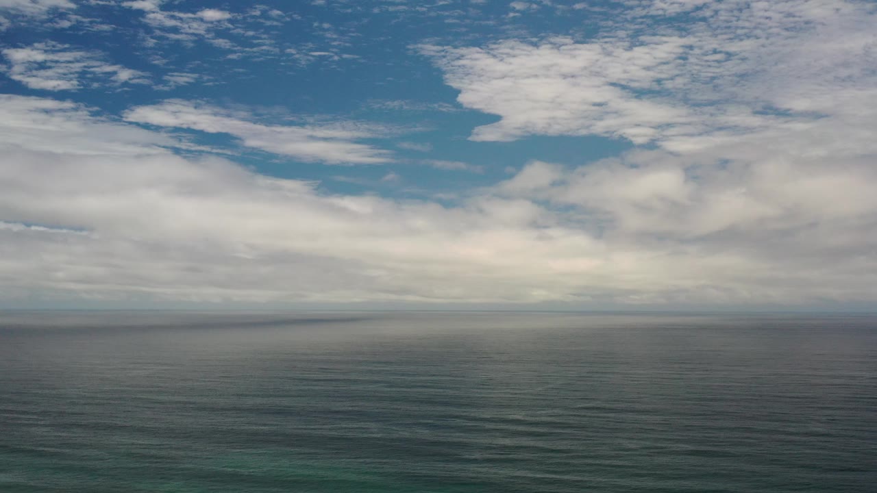 Open sea below a bright cloud layer and patches of blue sky.