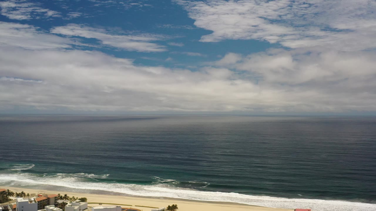 Wide ocean horizon with clouds and surf at the beach