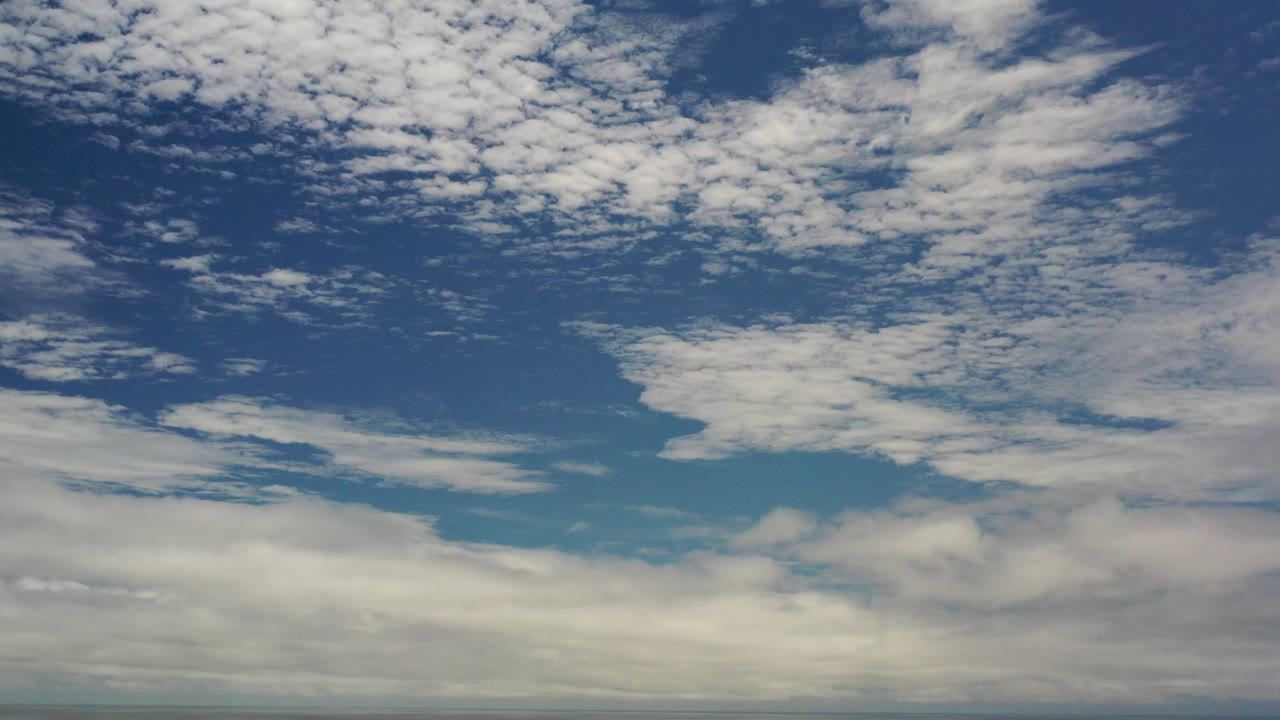 Opening frame of the Los Cabos, Mexico clip showing a blue sky with scattered white cloud texture, a softer gray-white cloud band near the bottom, and no visible people.