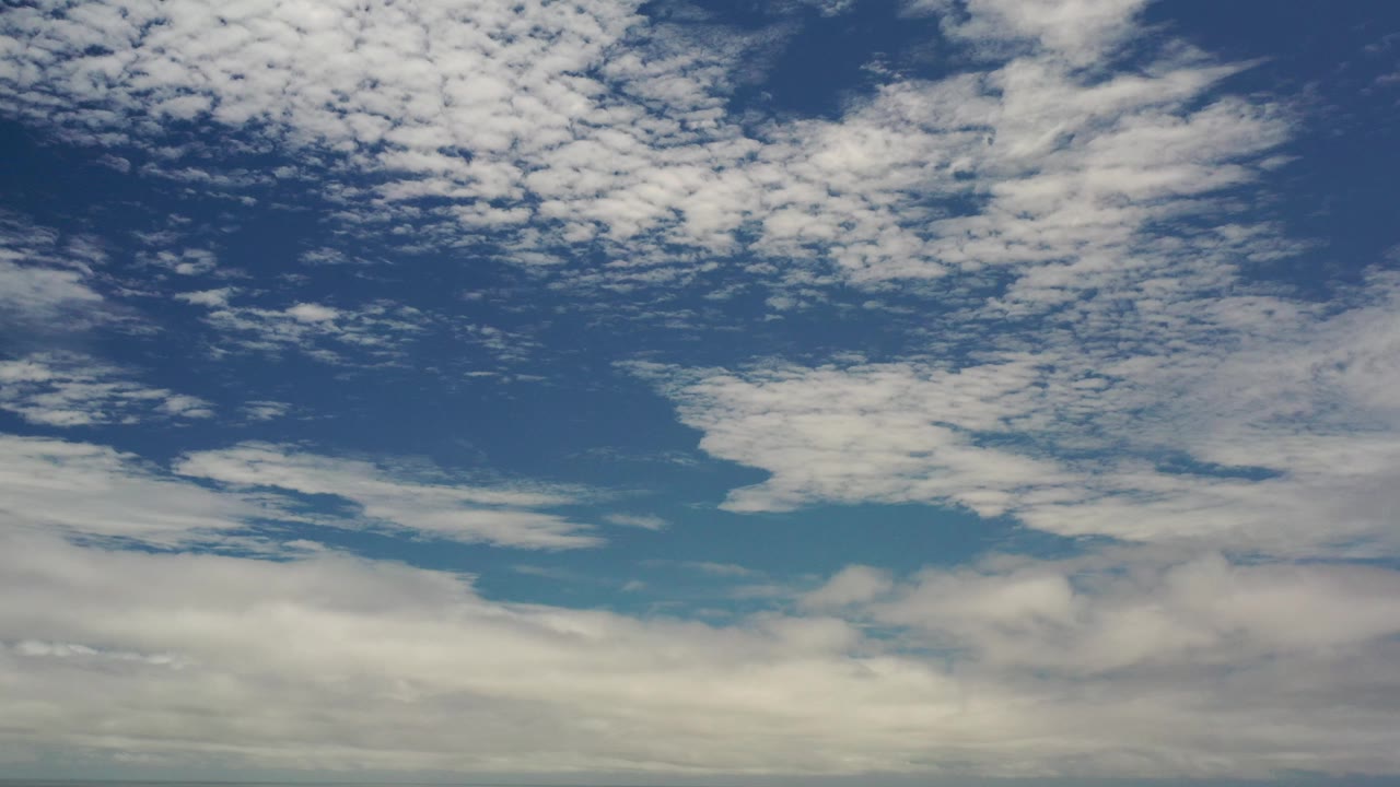 Cloudy blue sky with broken white cloud patches and muted lower cloud cover.