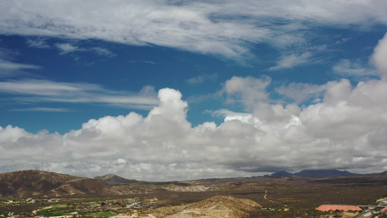 Low desert hills beneath large cumulus clouds