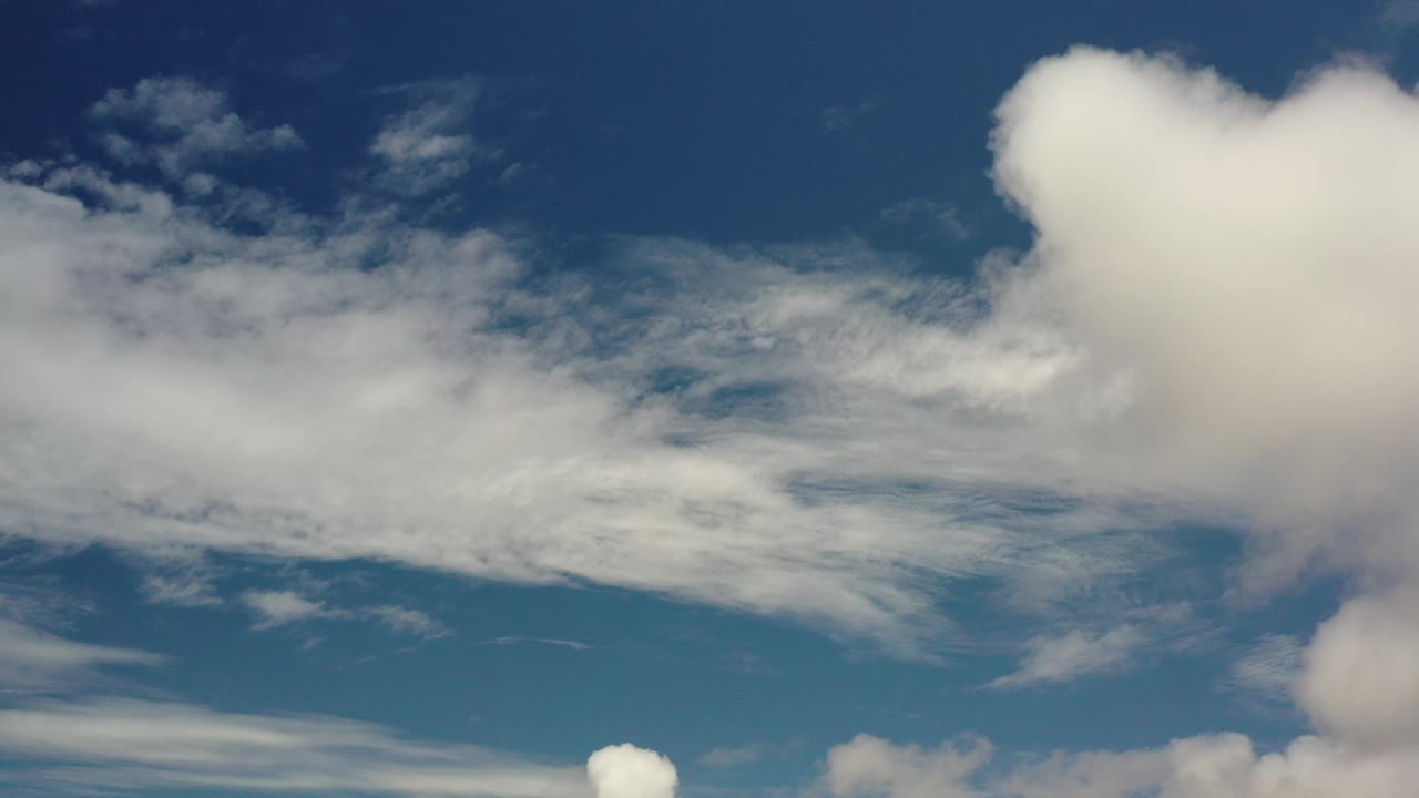 Layered white clouds under deep blue sky.