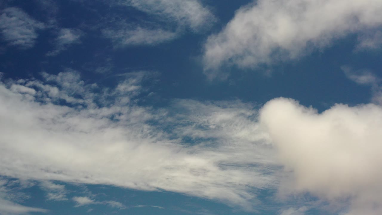 White clouds across a blue daytime sky.