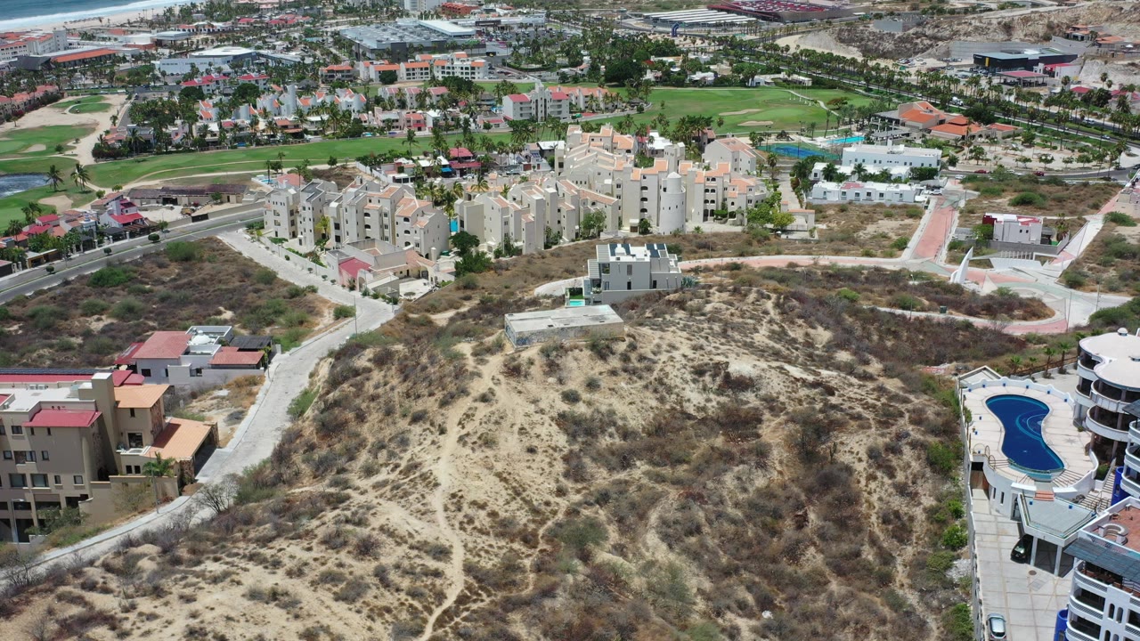 Aerial view of dry hillside, apartment buildings, roads, and a blue pool.