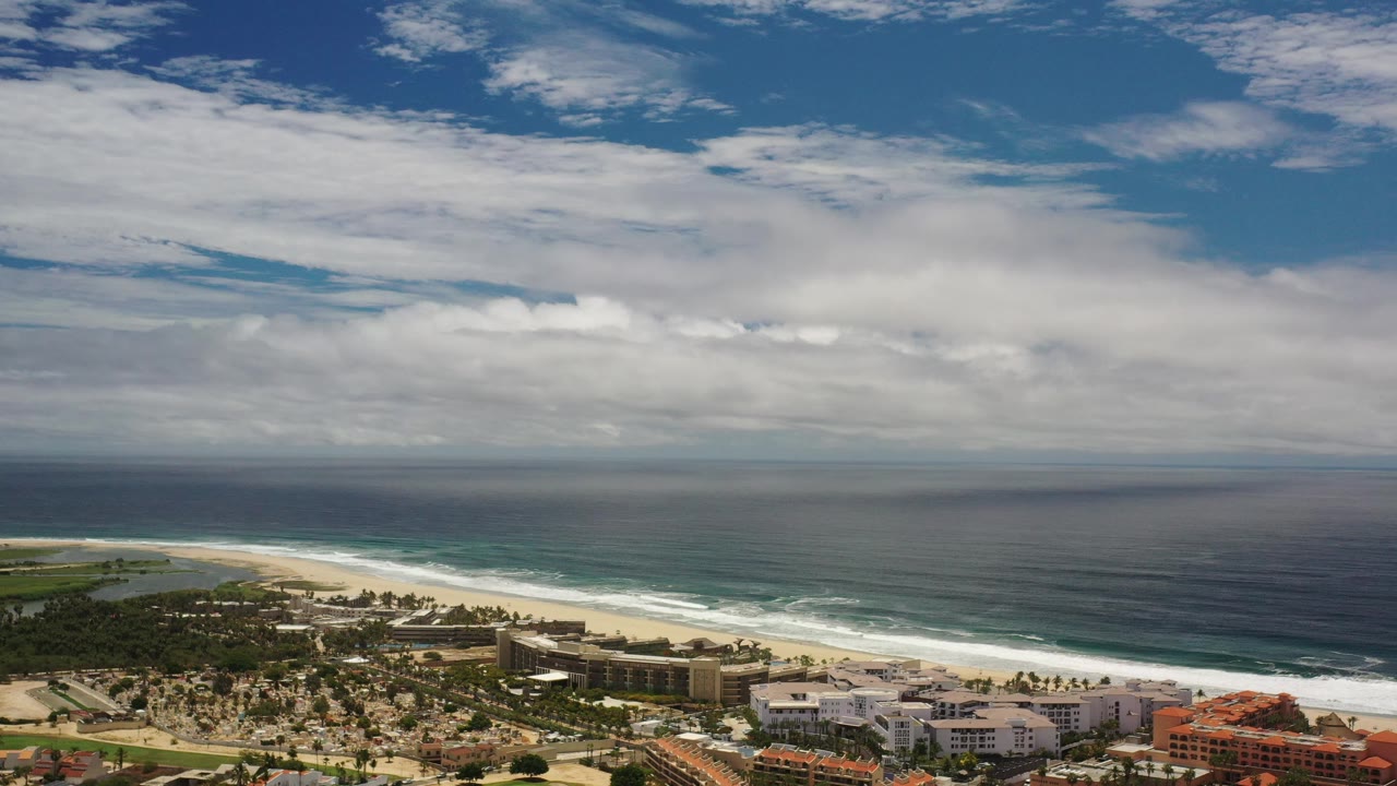 Coastal resort area beside surf and a dark blue ocean horizon.