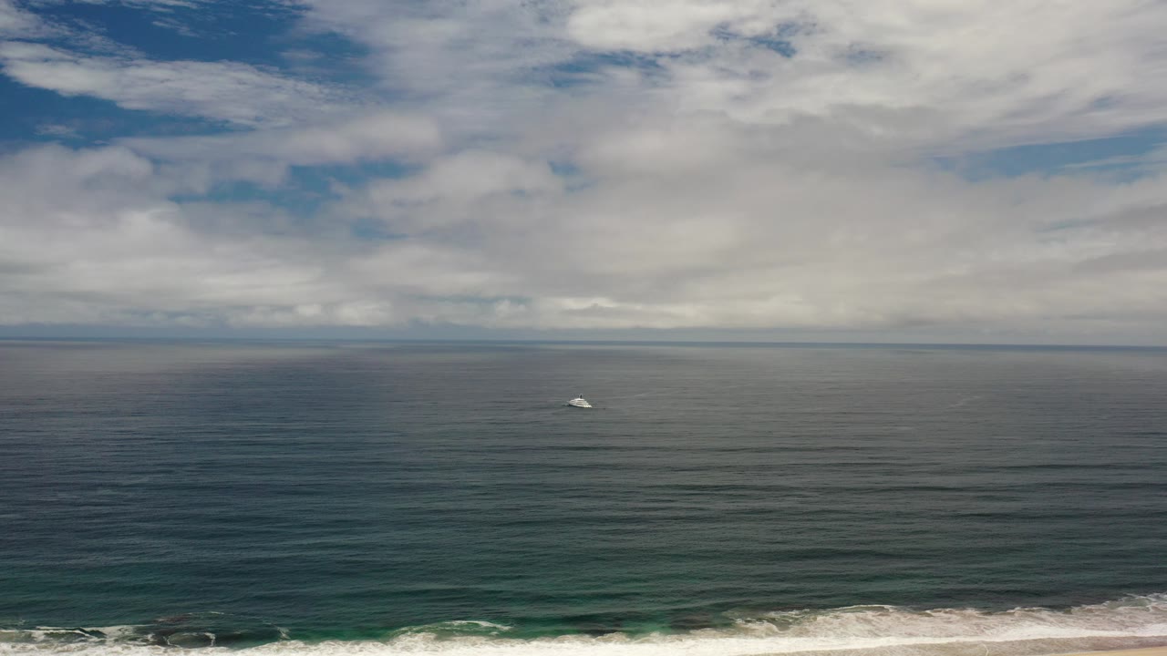Opening frame of open ocean in Los Cabos, Mexico, with a level horizon, broken white clouds, a narrow surf line, and no visible people.