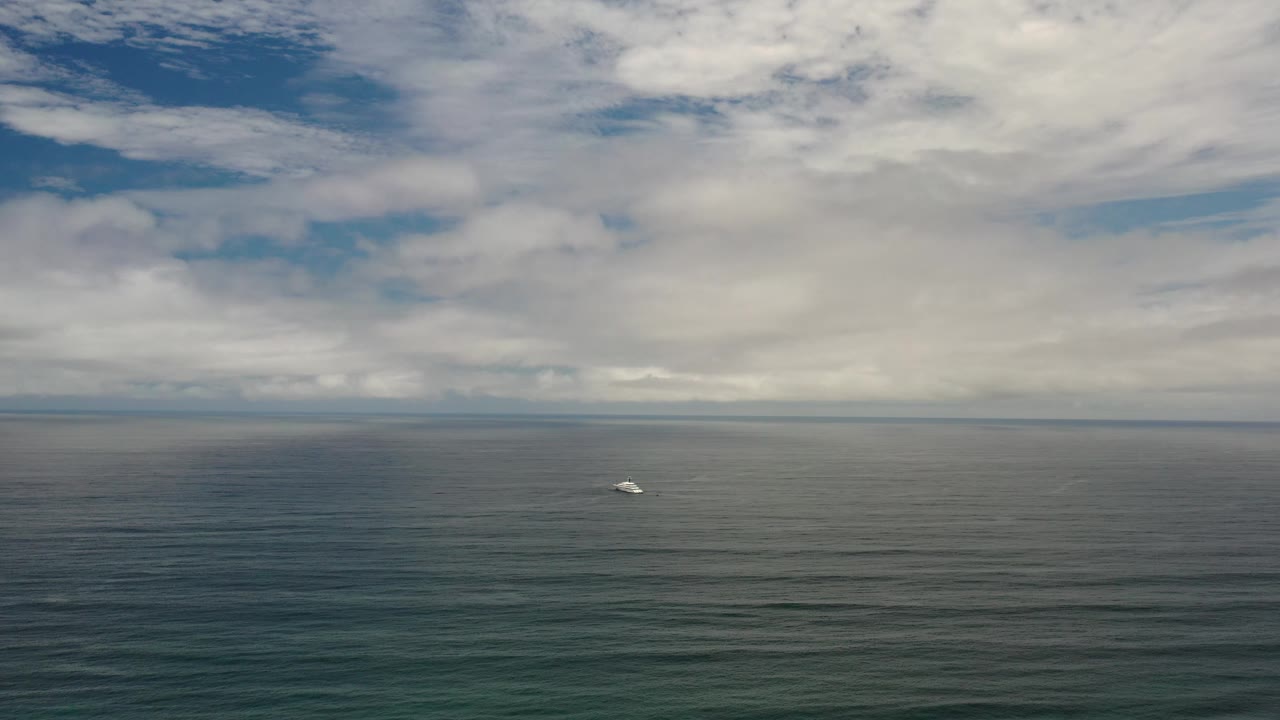 Distant white object on open water below a cloudy horizon