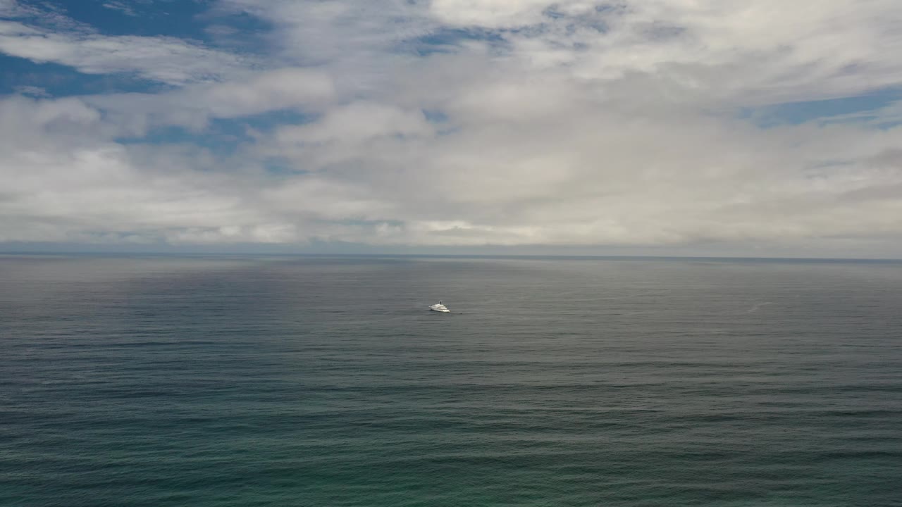 Tiny boat on blue-green water beneath white clouds.