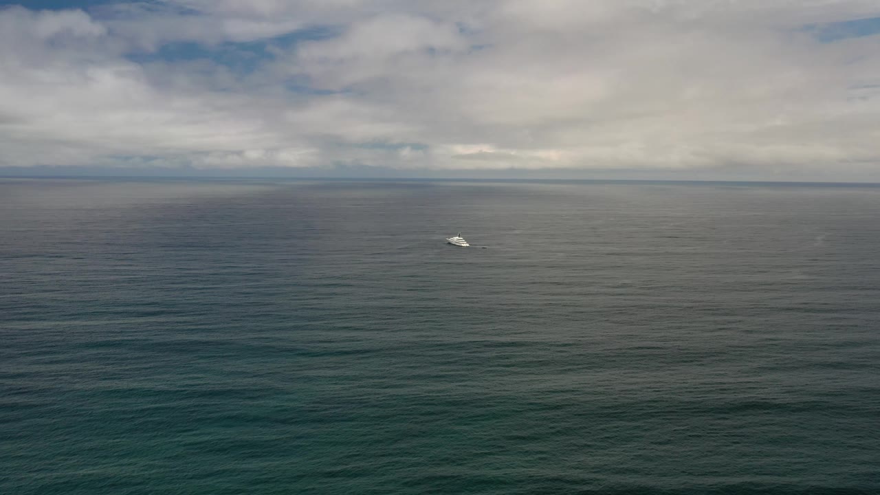 Small boat on dark ocean beneath a cloudy horizon