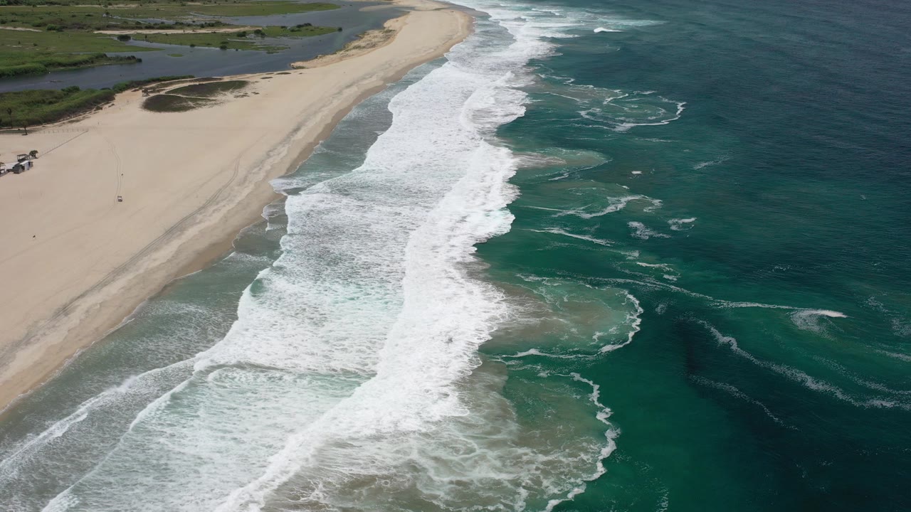 Aerial view of waves breaking along a sandy beach