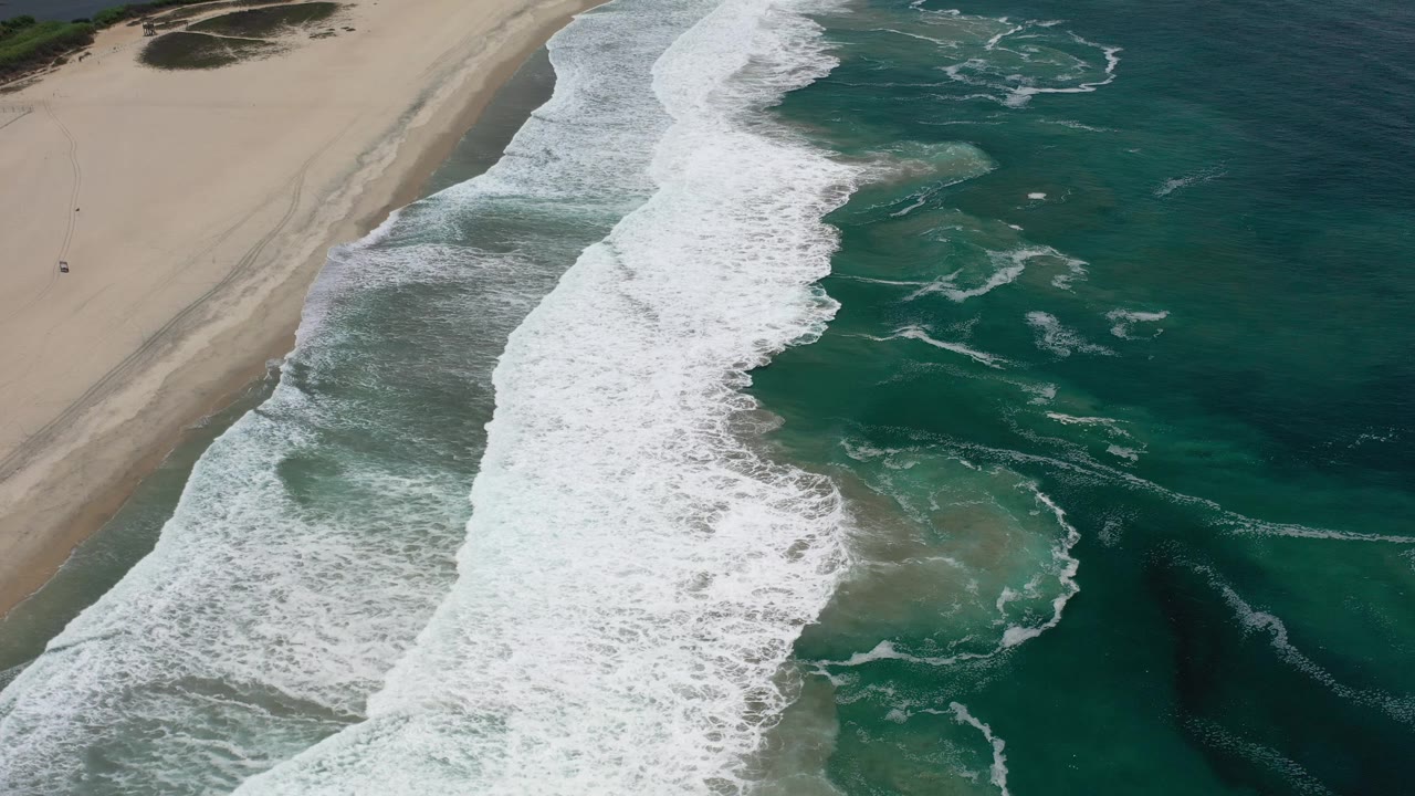 Foamy surf washing onto an empty beach