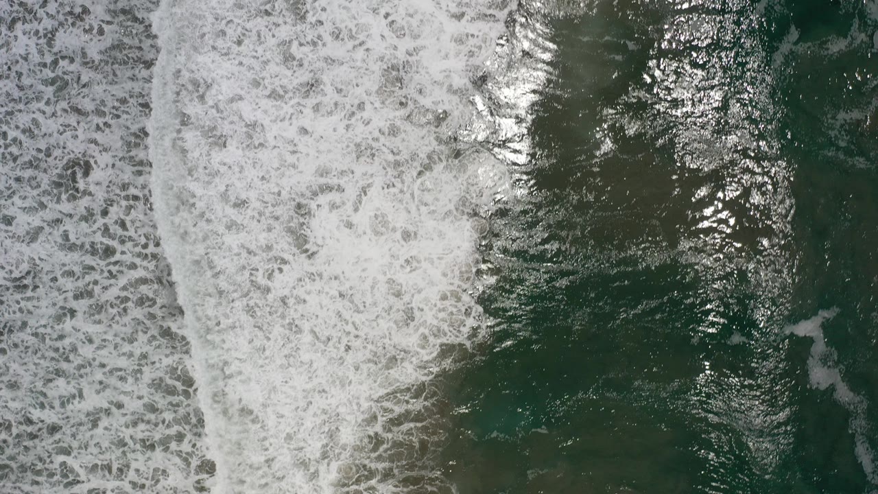 Overhead view of foamy waves crossing dark green ocean water in Los Cabos, Mexico, with no visible people.