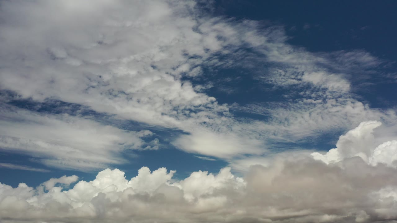 Blue sky with layered white and gray cumulus clouds.