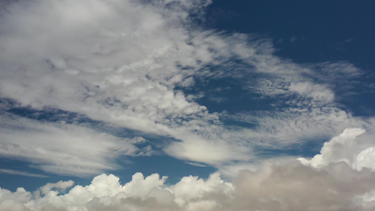 Opening frame of the Los Cabos sky view with streaked high clouds across deep blue sky and thicker white cloud tops along the bottom, no visible people.