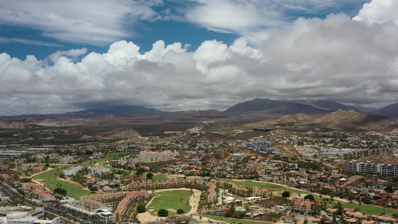 Aerial view of a city below dry hills and large clouds