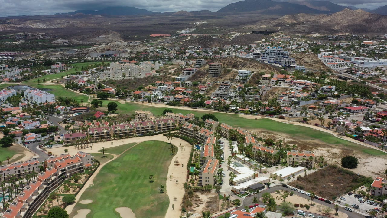 Aerial view of a golf course and residential neighborhood near dry hills.