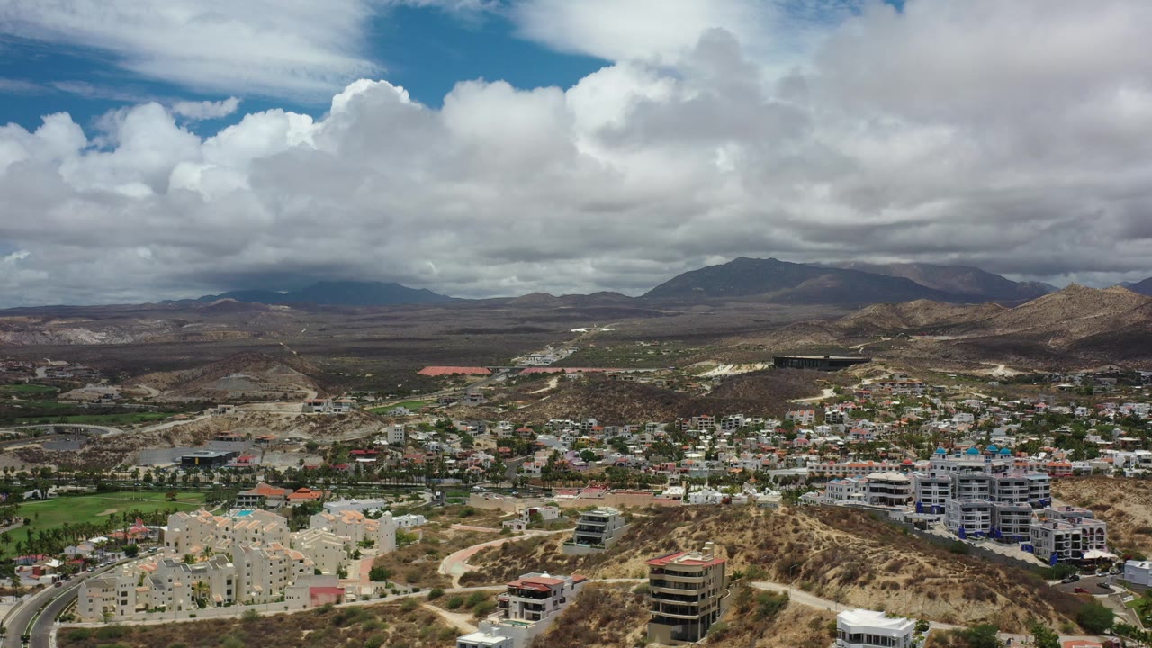 City buildings and roads spread across dry hills beneath clouds.