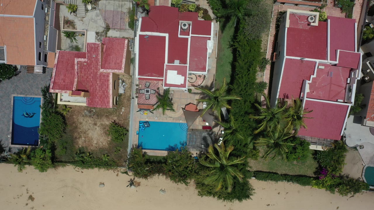 Overhead view of coral-roofed homes beside pools and palms