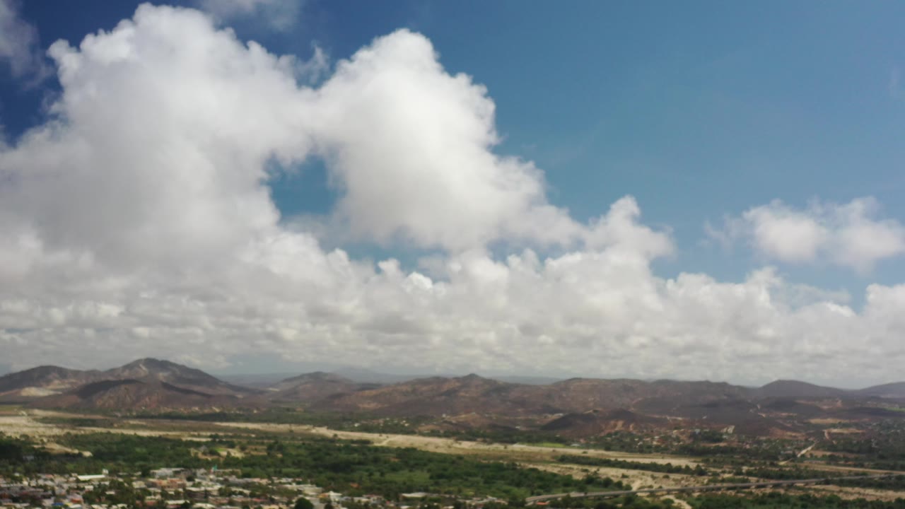 Puffy white clouds above a mountain ridge and open valley