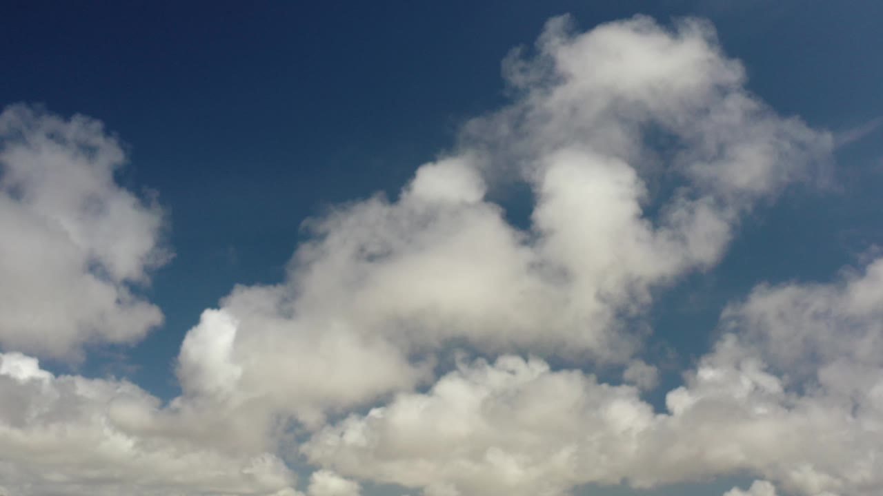 Opening frame of white and gray cumulus clouds over a deep blue sky in Los Cabos, Mexico, with no visible people.