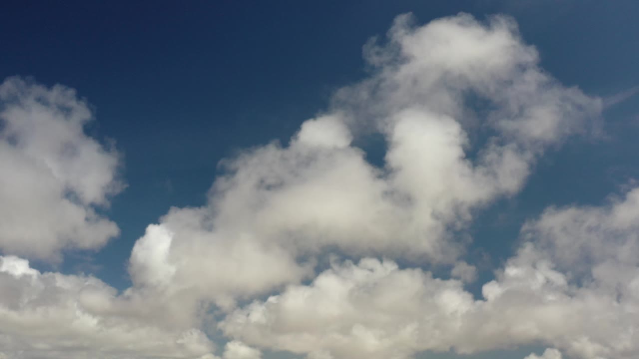 Cumulus clouds spread across a blue sky.