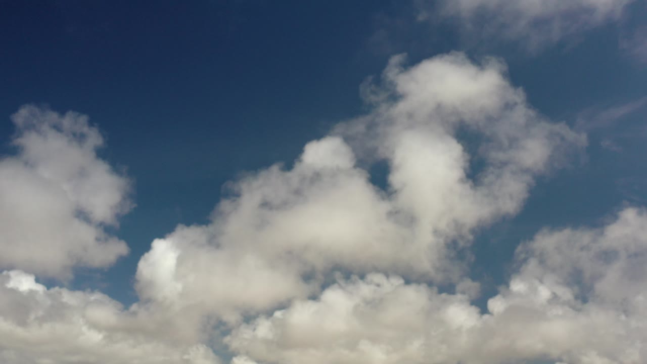 Opening frame of the Los Cabos, Mexico clip showing soft white clouds spread across a deep blue sky with no visible people or buildings.