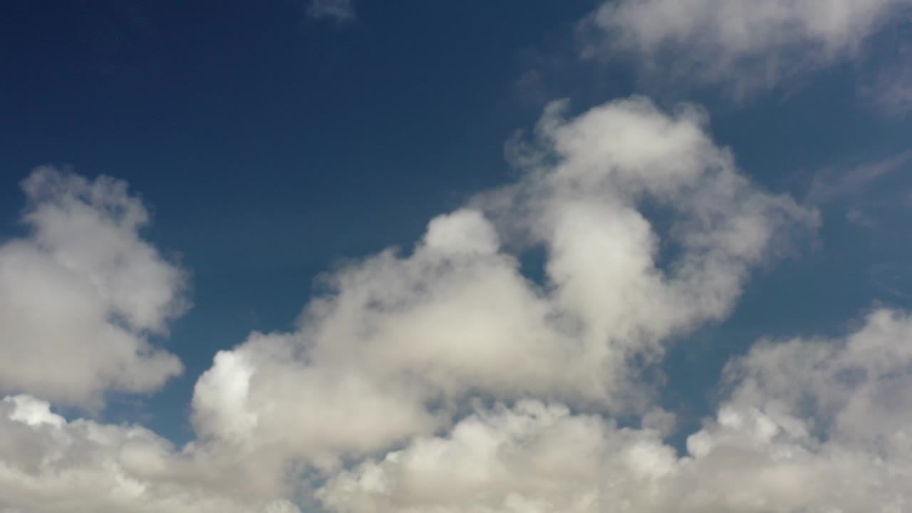 White and gray clouds drifting across blue sky.