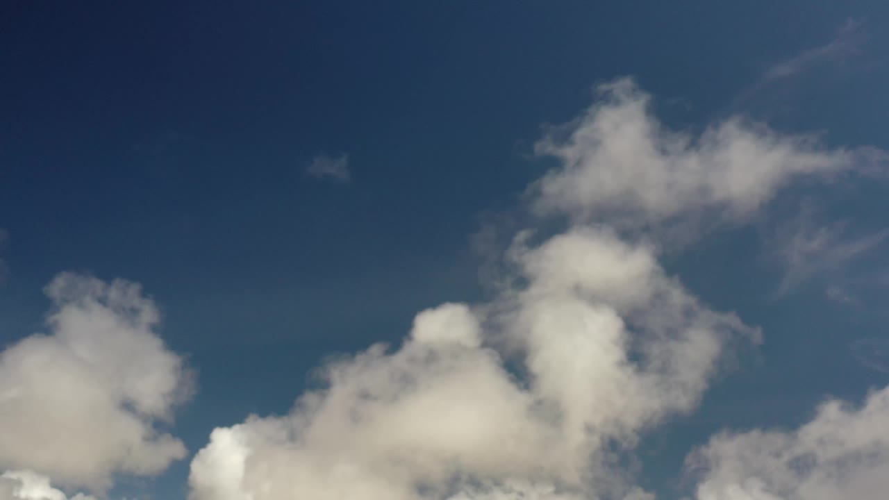 A later Los Cabos sky frame shows a taller white cloud mass near center with open dark blue sky above and no visible people.