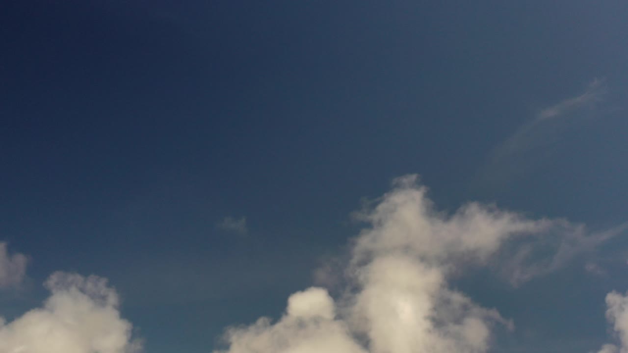 Opening frame of a Los Cabos, Mexico sky view with white clouds low in the frame, deep blue open space above, and no visible people.