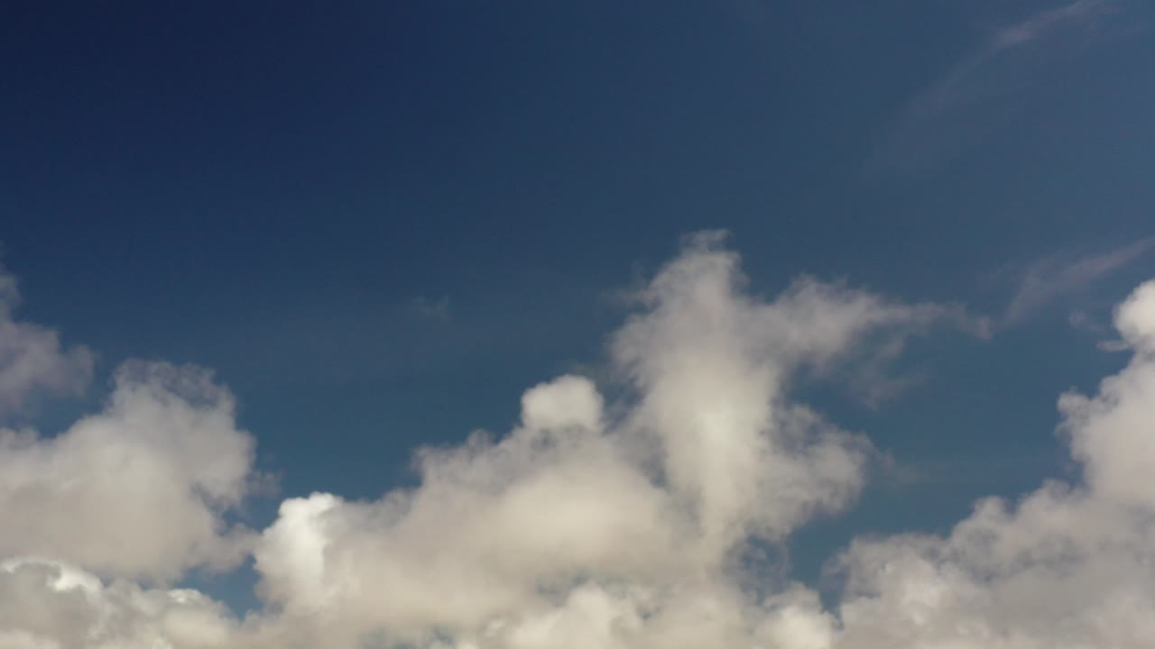 Opening frame of the Los Cabos clip showing deep blue sky above clustered white clouds, with no visible people.
