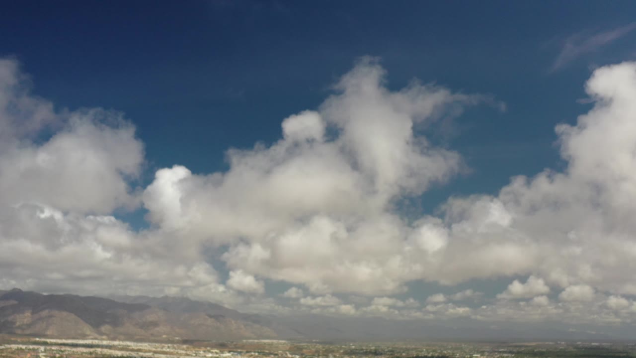 Bright clouds over mountains with low city detail below.