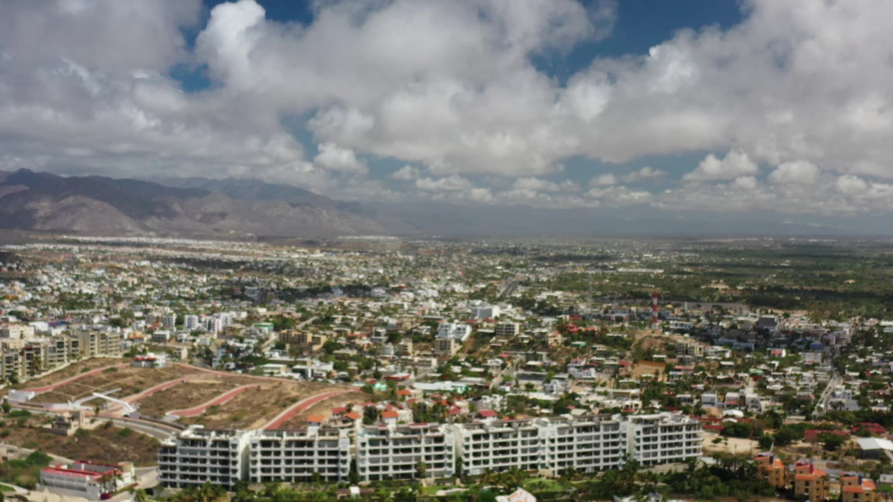 Los Cabos urban panorama with mountains beneath scattered white clouds