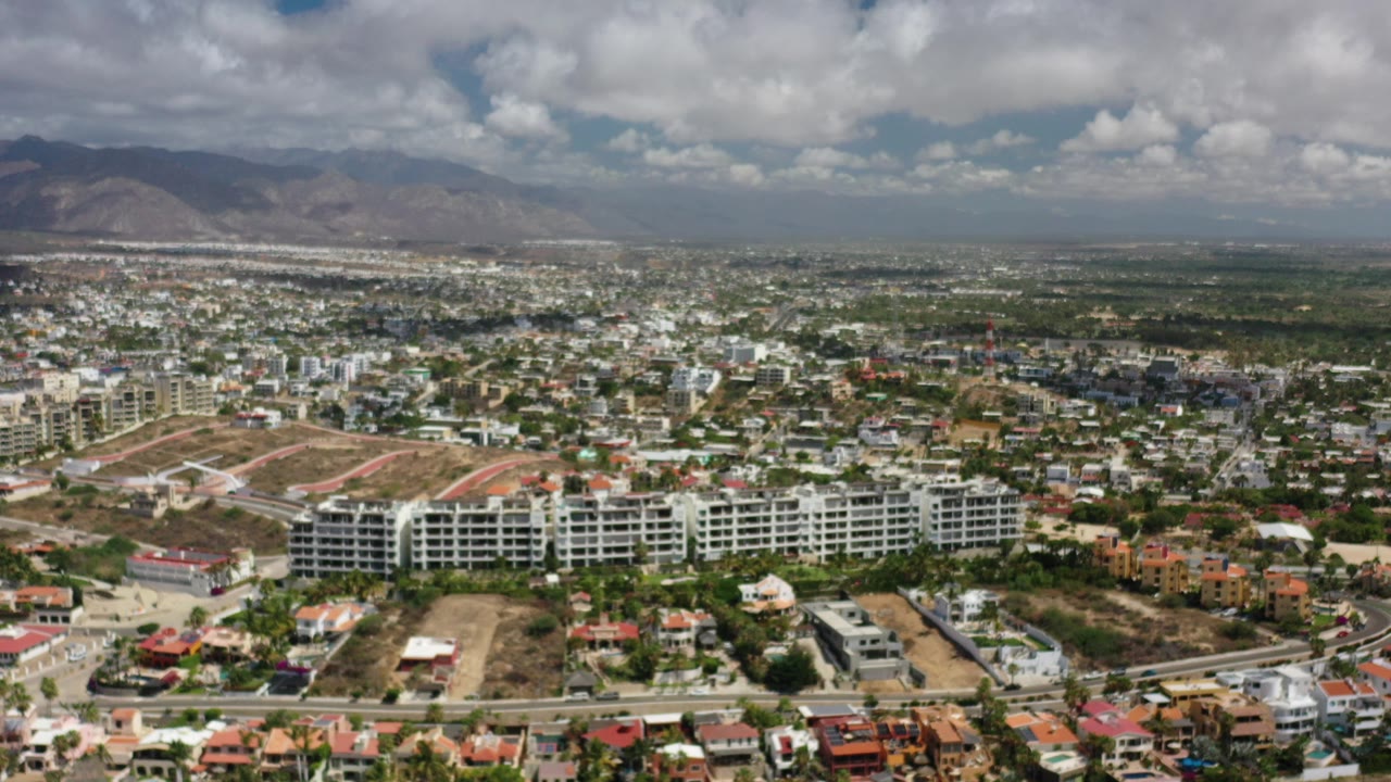 Wide aerial view of Los Cabos neighborhoods with mountains and clouds