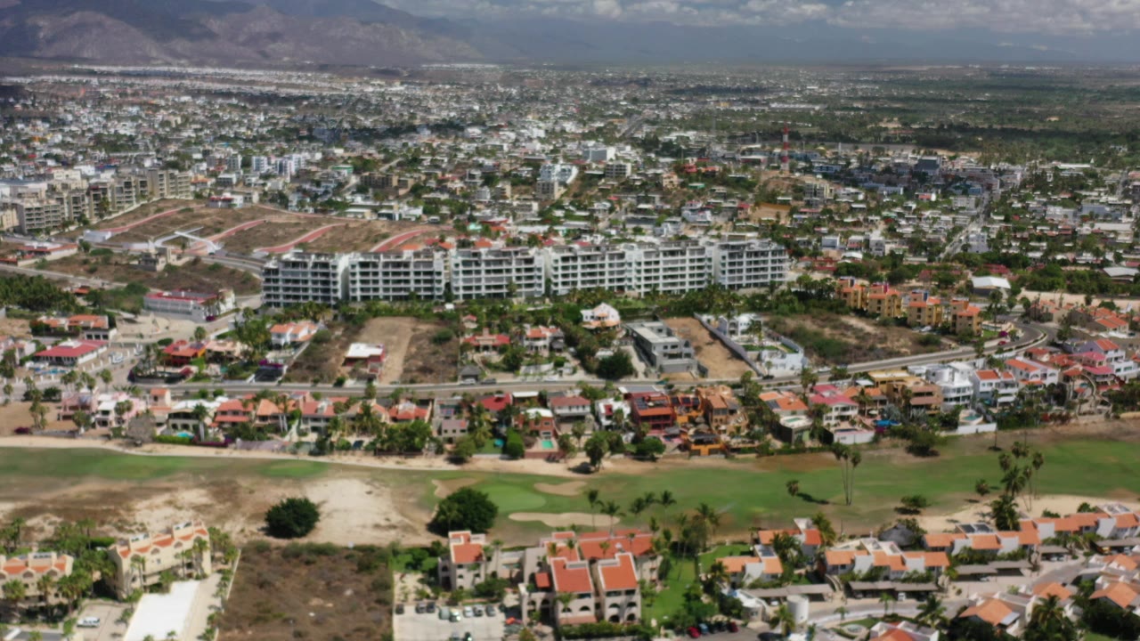 Aerial view of residential buildings, green grounds, and distant hills