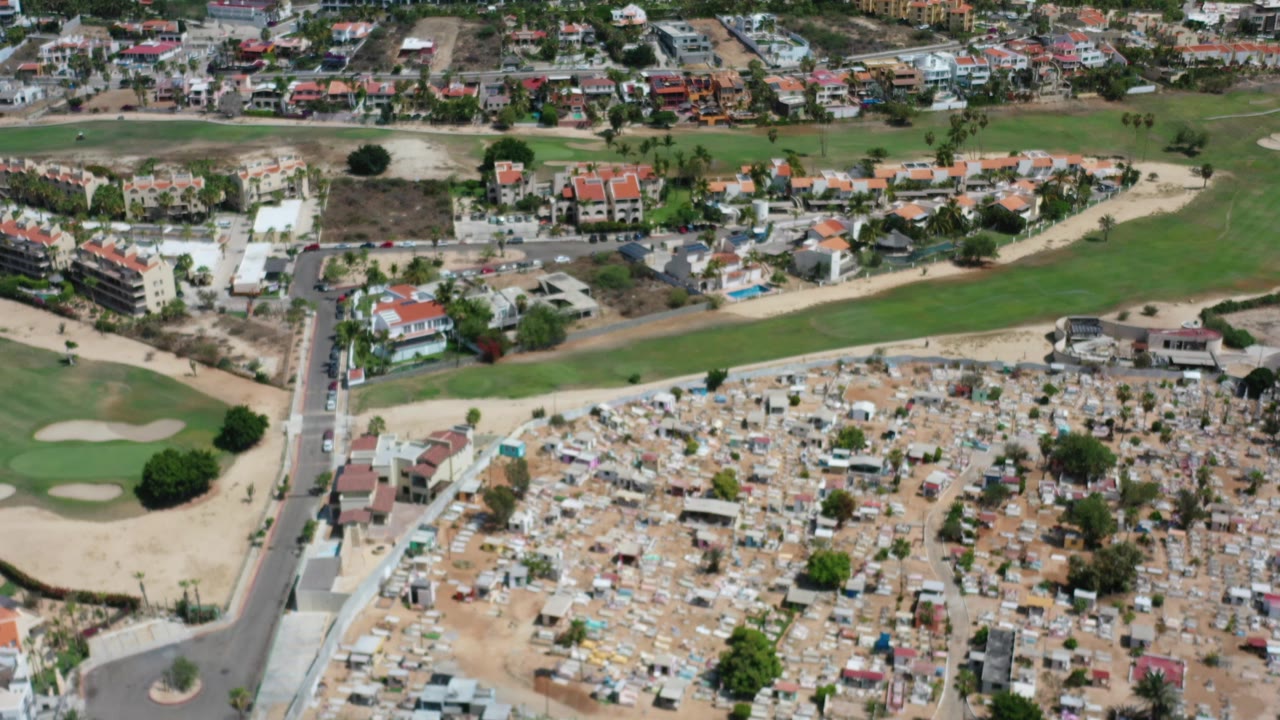 Aerial view of cemetery, golf course, roads, and residential buildings.