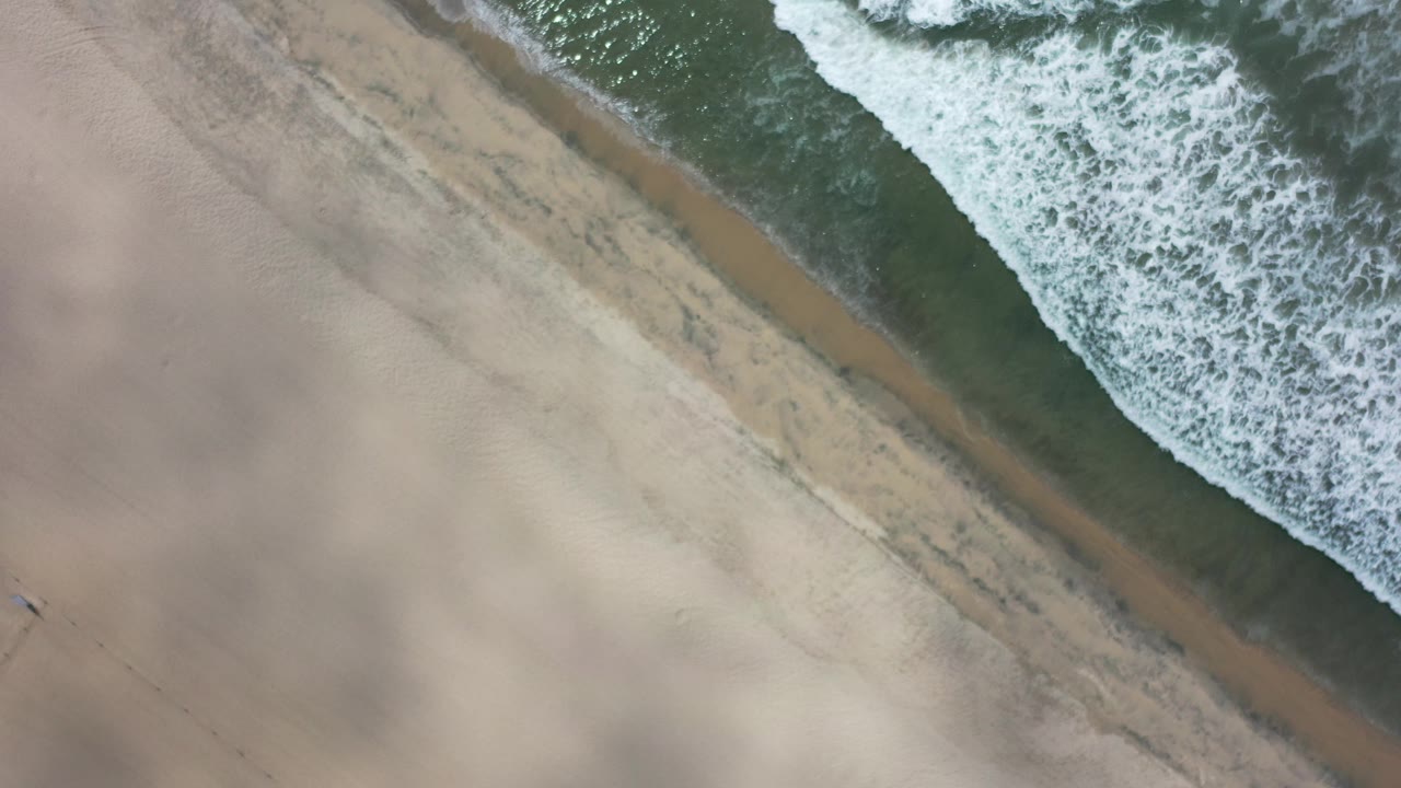 Overhead surf line crossing tan sand