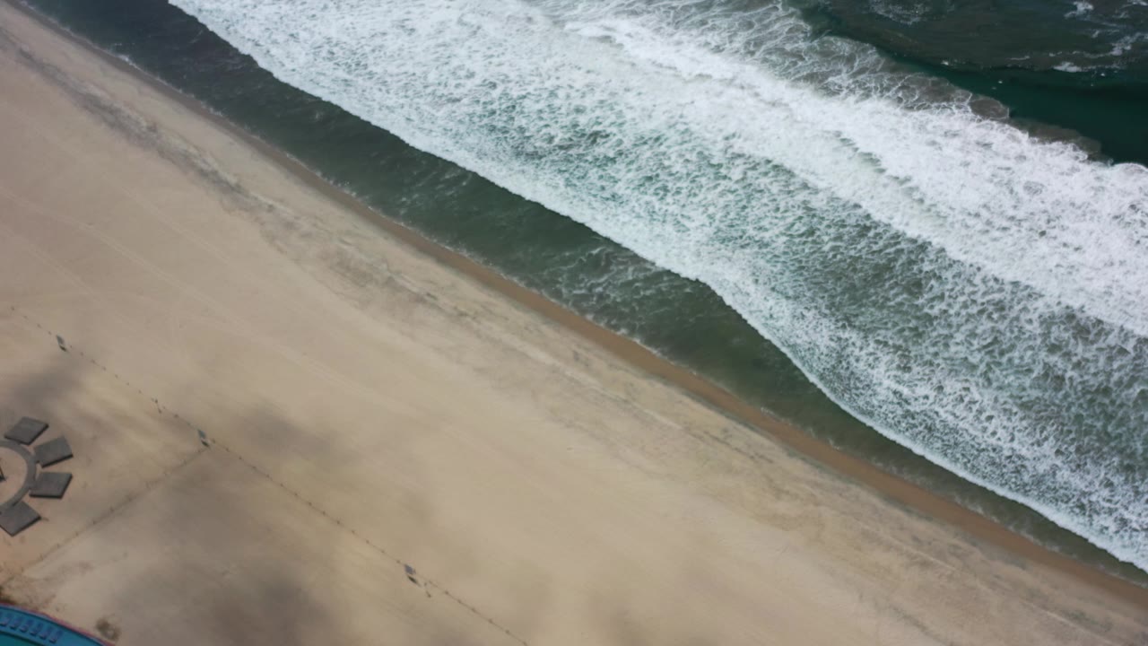 Foam-covered wave line beside open beach sand.