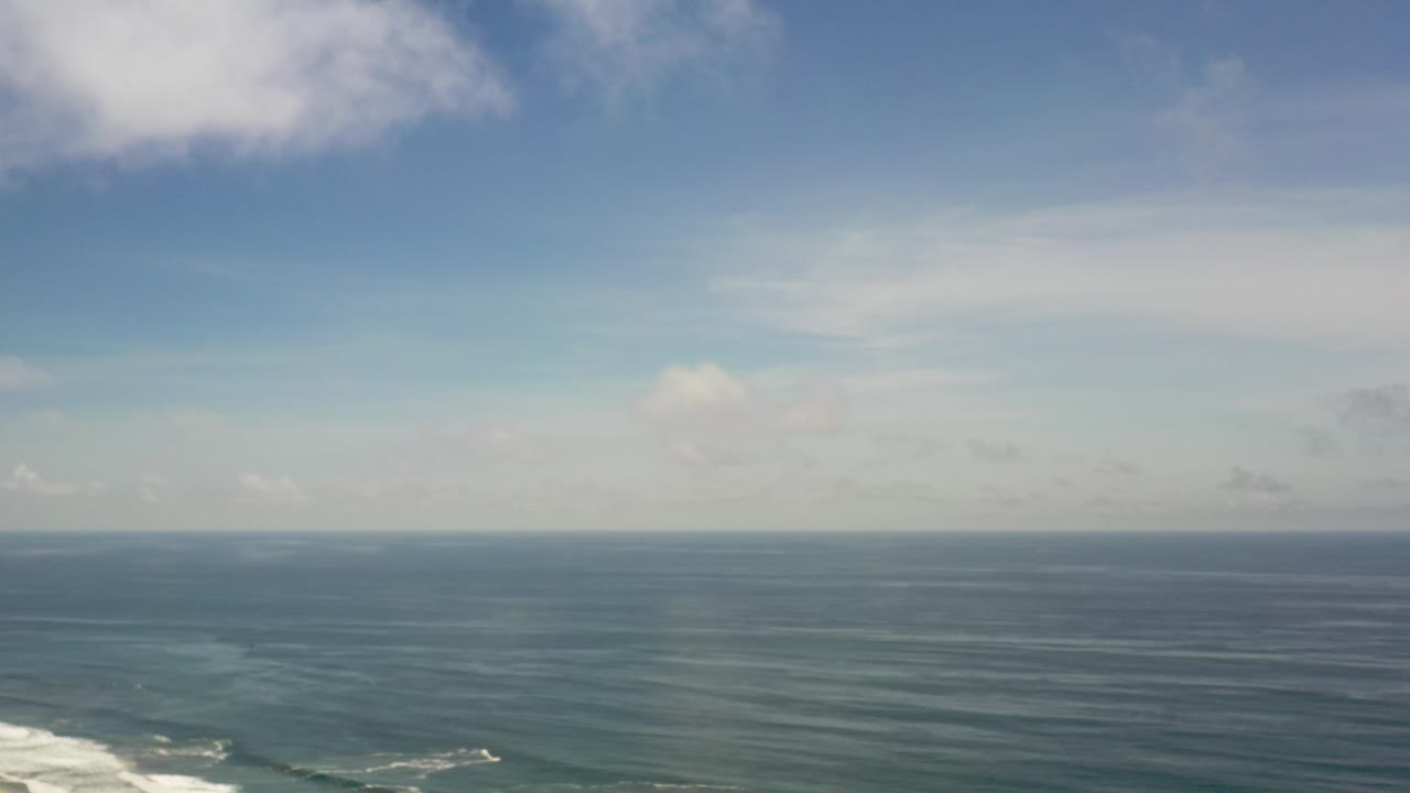 Blue ocean horizon beneath scattered clouds